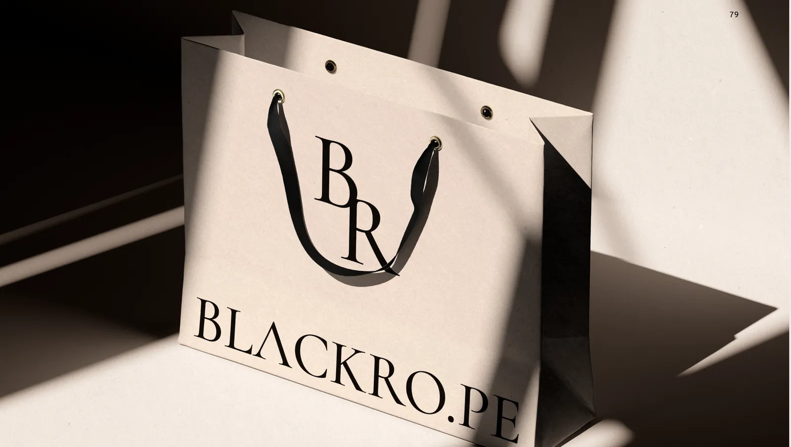 A cream carrier bag in raking light, the serif monogram and the wordmark printed across the front.