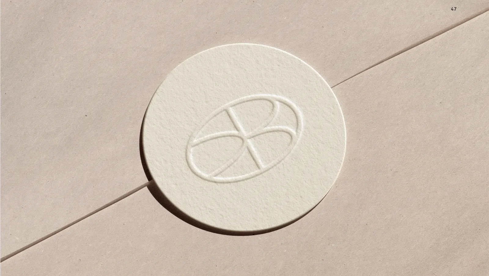 A blind embossed paper seal, the oval monogram pressed into the stock.