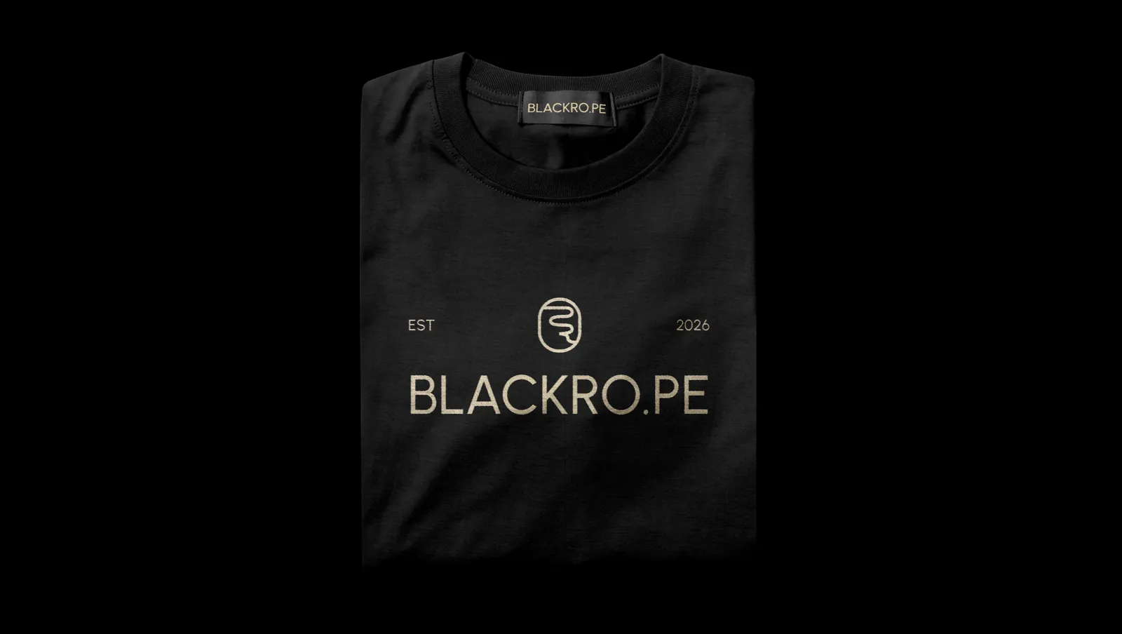 A folded black t-shirt, the rope loop and the wordmark printed in gold across the chest.