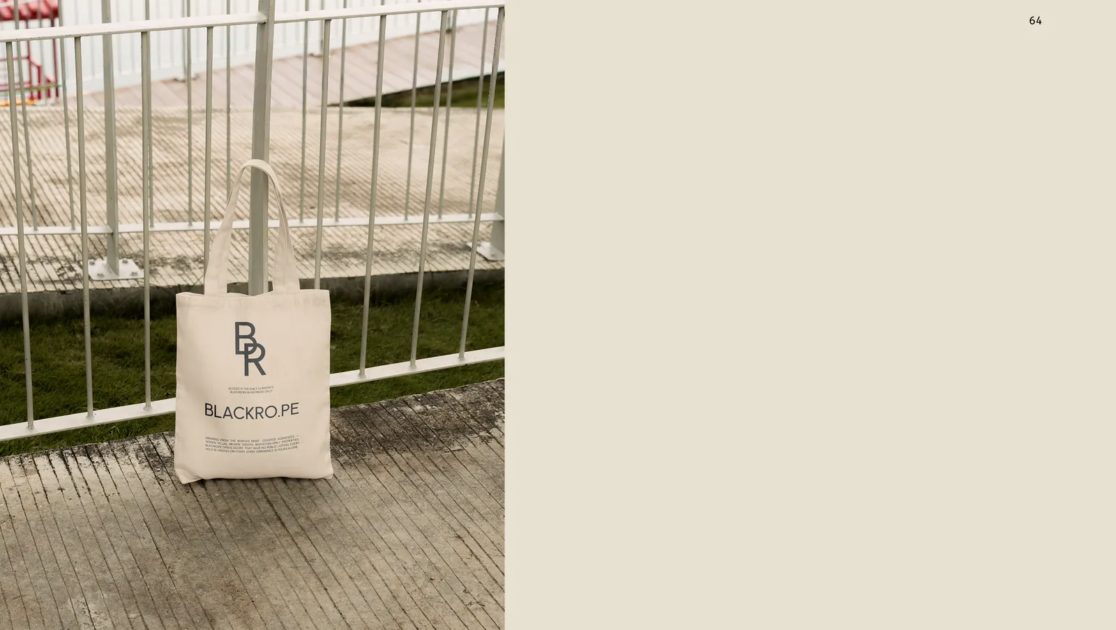 A canvas tote hung against railings, the serif monogram over the wordmark.