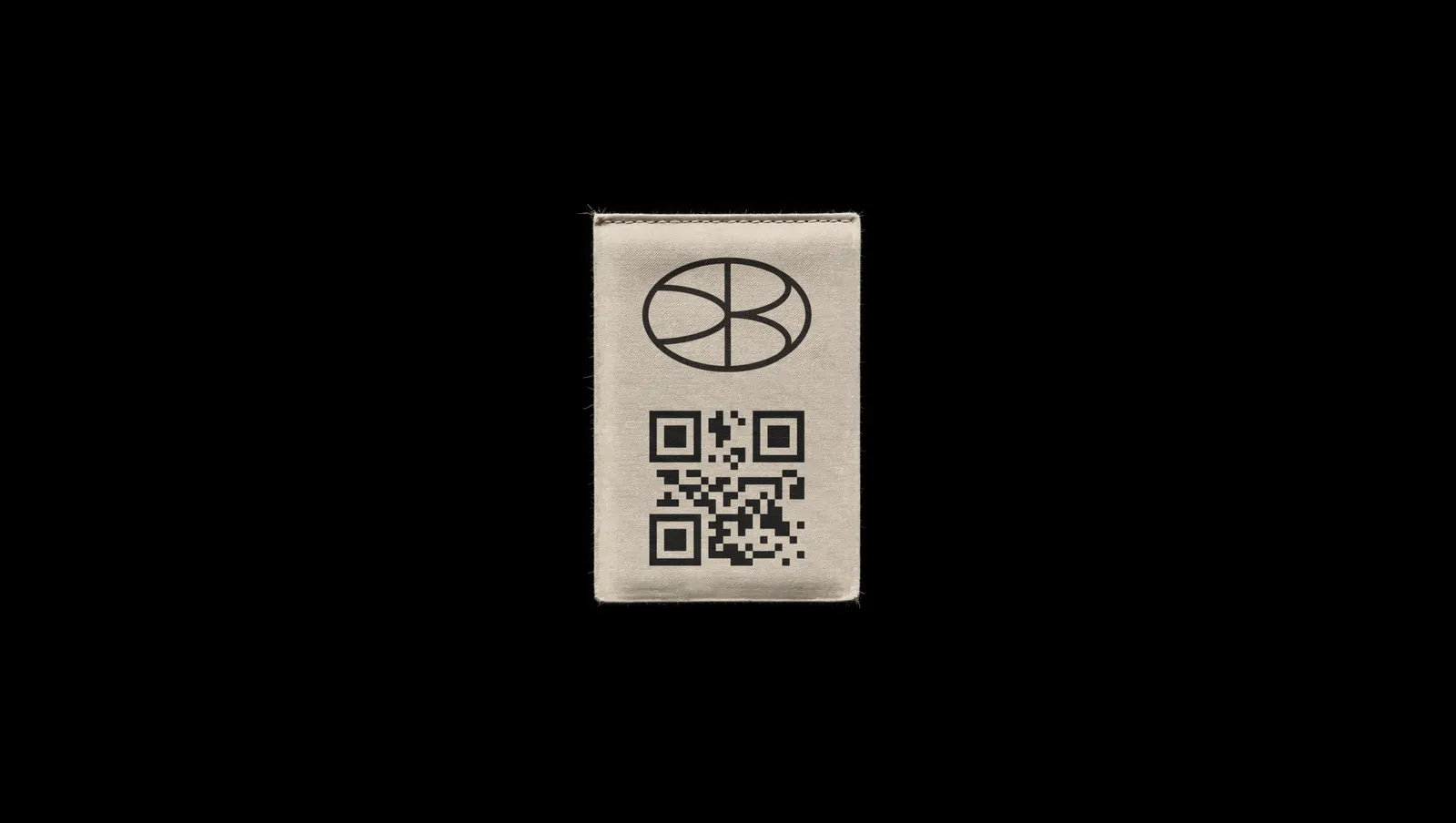 A stitched fabric patch, the oval monogram above a QR code.