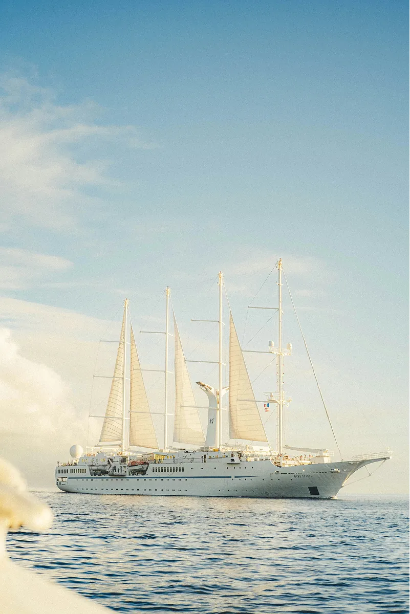 A four masted sailing yacht at anchor in open water.